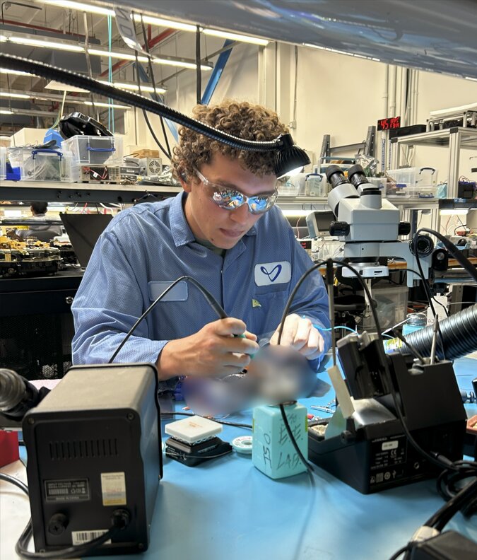 Romain soldering a circuit board at a workbench in Joby's lab