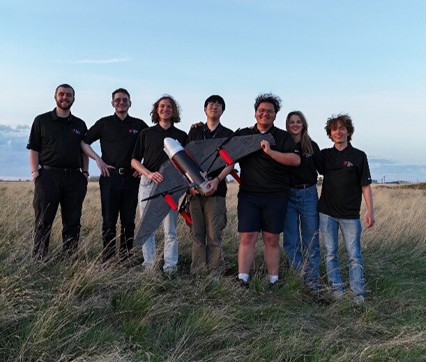 McGill Aerial Design team holding a fixed-wing drone in a field