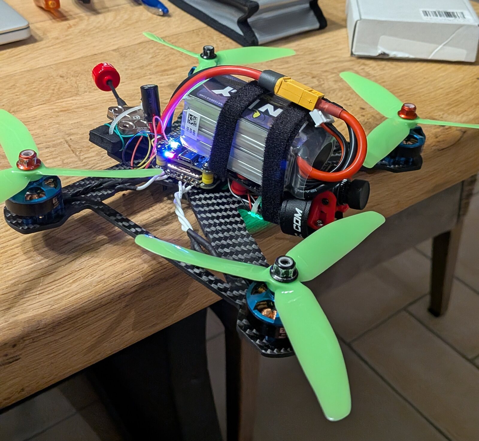 Close-up of the FPV drone build on a workbench, battery strapped to the stack