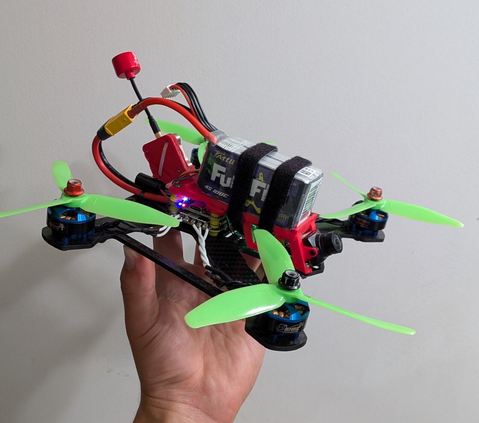 Rebuilt FPV drone held up against a plain background, showing the TPU midframe