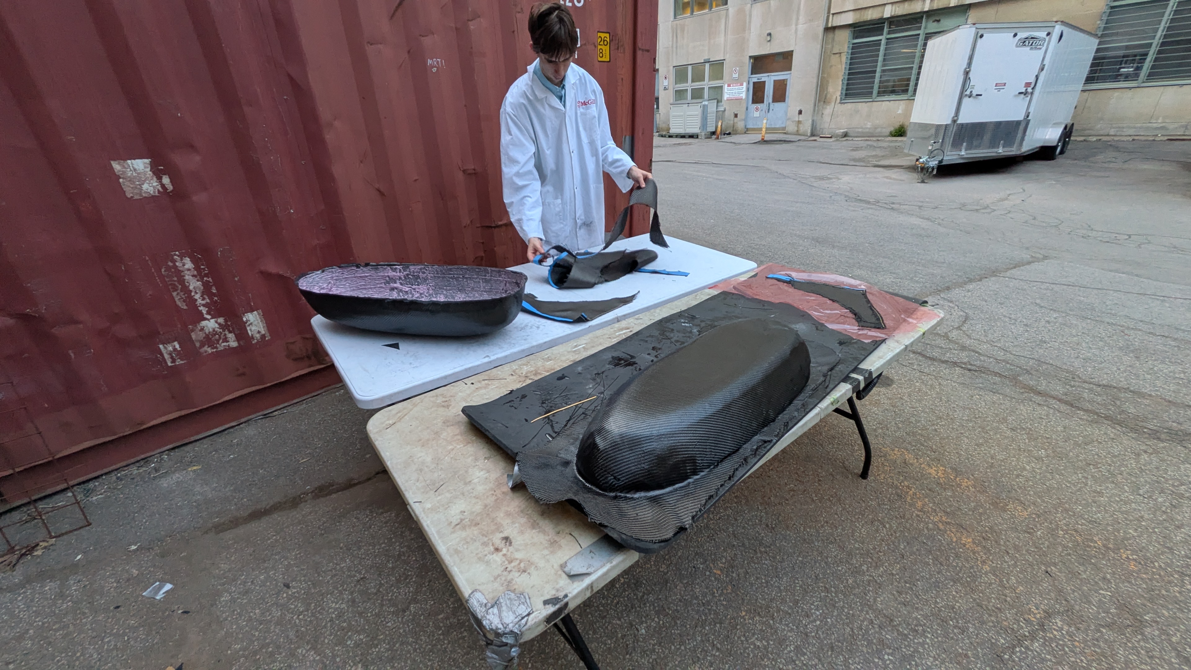 Romain in a lab coat working with carbon fiber composite molds outside the McGill Aerial Design shop