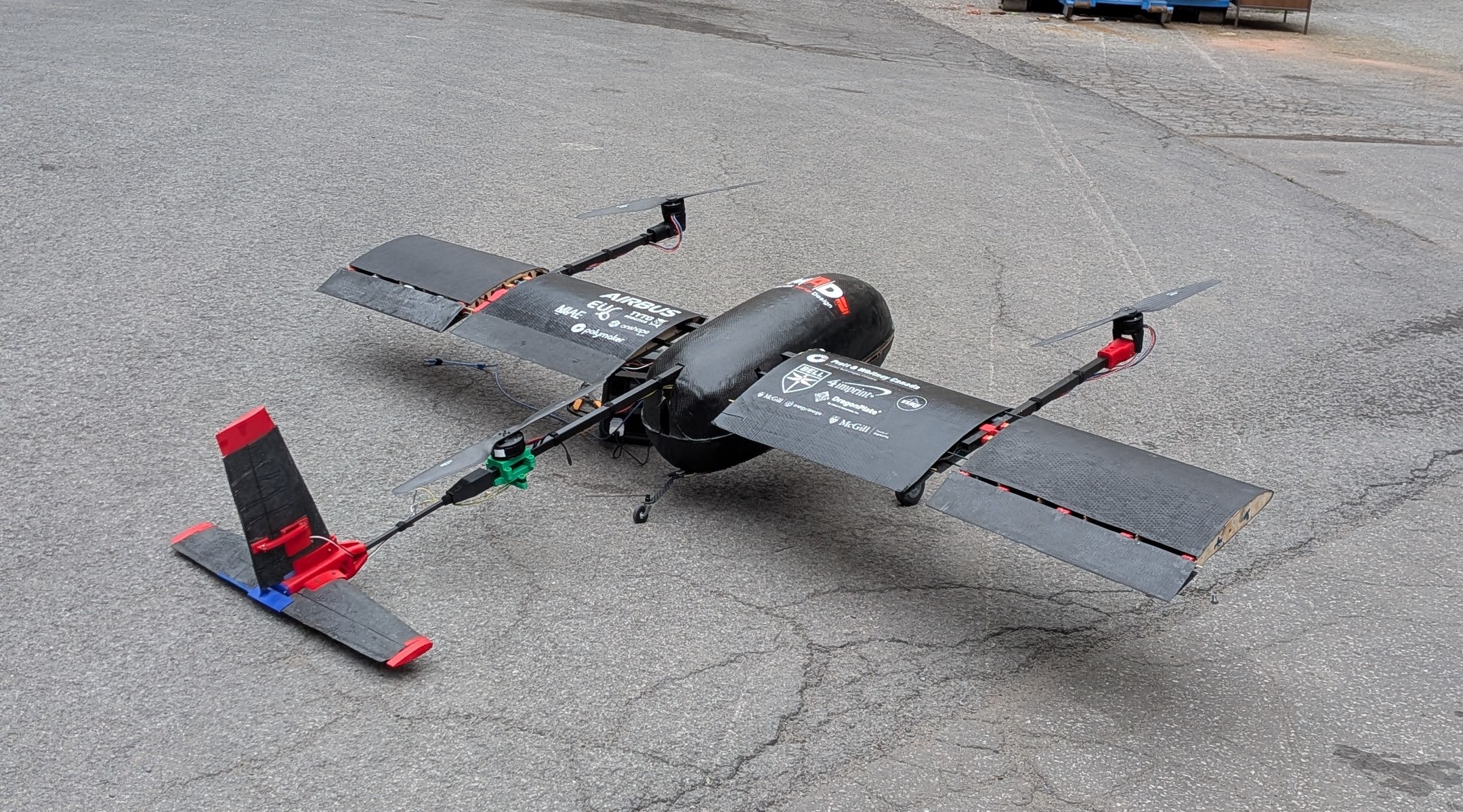 Assembled Tilt-Rotor aircraft resting on pavement, tilt-rotor booms and three-piece tail visible